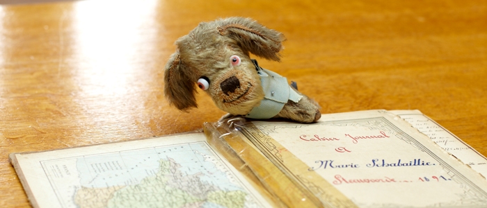 ‘Adolphus’, a toy dog given to Major Maurice Le Blanc Smith by a French girl & used as a mascot in his flying missions in France; an abandoned French school exercise book found by a British soldier. Liddle Collection
